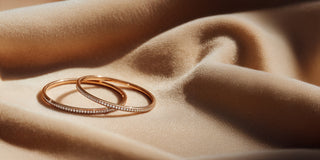 Réia pair of rose gold diamond bangles with lab-grown diamonds on velvet fabric.