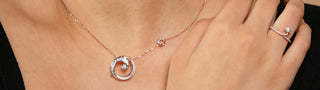 Close-up of a woman wearing a rose gold necklace with a spiral lab-grown diamond pendant and a matching ring.
