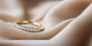 Réia yellow gold band ring with a row of lab-grown diamonds on satin fabric.