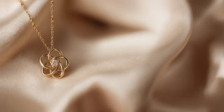 Réia yellow gold pendant necklace with a flower design and a central lab-grown diamond, displayed on champagne fabric.