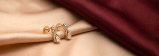 Réia yellow gold ring featuring a marquise-cut lab-grown diamond cluster, displayed on champagne fabric next to dried floral accents.
