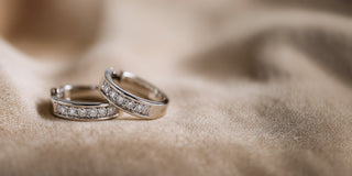 Réia pair of white gold hoop earrings with channel-set lab-grown diamonds, displayed on beige fabric.