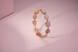 A rose gold bracelet featuring a sequence of various shaped lab-grown diamond settings on a soft pink background.