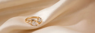 A Réia white gold engagement ring featuring a round lab-grown diamond on a pavé band, resting on sand.