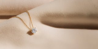 Réia yellow gold pendant necklace with a round lab-grown diamond, displayed on beige fabric.