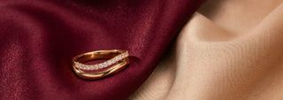 A Réia yellow gold ring with a emerald cut lab-grown diamond and floral diamond side accents, resting on beige fabric with dried flowers.