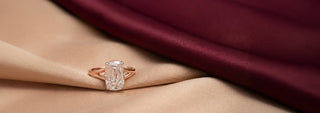 A Reia rose gold solitaire ring features a six-prong setting holding a round brilliant lab-grown diamond, resting on textured beige fabric.