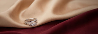 A Réia yellow gold engagement set with an oval lab-grown diamond and a matching lab-grown diamond eternity band, resting on draped satin fabric.