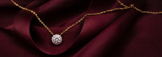 A Réia yellow gold pendant with a lab-grown diamond center stone surrounded by a small diamond halo, worn close to the neck.