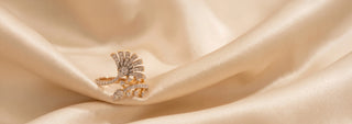 A gold tiered necklace features many small lab-grown diamonds and two large green lab-grown diamonds, on a white surface.