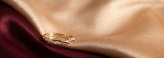 Réia pair of yellow gold wedding bands, one plain and one set with lab-grown diamonds, on beige fabric.