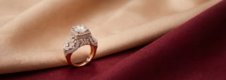 A Reia yellow gold engagement ring features a large square-cut lab-grown diamond on a pavé band, resting on fine pale beach sand.