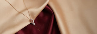 A Réia rose gold chain necklace with a twisting spiral pendant set with lines of lab-grown diamonds, worn on a person's neck.