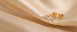 Side view of round lab-grown diamond solitaire nose pins in 18 KT yellow gold, featuring round brilliant diamonds in classic four-prong settings with secure screw-back closures.