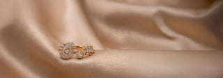 Yellow gold lab-grown diamond stud earrings, shaped like leafy branches, rest on beige fabric next to dried wheat stems.