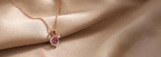 Réia rose gold swan pendant necklace with lab-grown diamonds, displayed on champagne fabric.