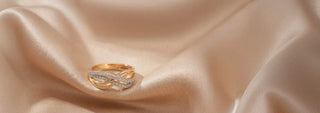A yellow gold lab-grown diamond solitaire ring features a round brilliant cut stone in a six-prong setting, resting on soft beige fabric.