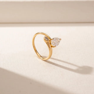 Angled view of a 14KT Yellow Gold ring featuring a pear-cut centre diamond and a curved band with a pear-shaped diamond accent.