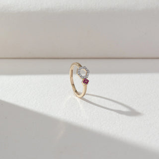 Angled view of Hexagon Diamond Open Ring in 14KT Yellow Gold, featuring lab grown diamonds in a hexagon halo with a pink gemstone cluster accent. Set on a beige backdrop, the design highlights modern contrast and elegance.

