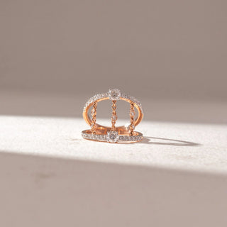 Front view of open double-band ring in yellow gold with pavé diamonds and dangling chain-set diamonds, set on a soft neutral surface, highlighting layered design and delicate movement.
