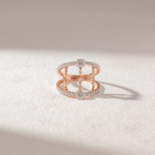 Top view of open double-band ring in yellow gold with pavé diamonds and chain-linked diamond accents, set on a soft neutral surface, highlighting layered design and delicate sparkle.
