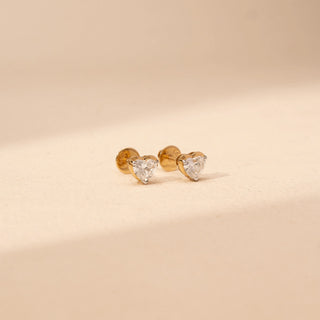 Side view of heart-shaped lab-grown diamond stud earrings in 14 KT yellow gold, featuring three-prong heart-cut solitaire diamonds in a timeless romantic design.