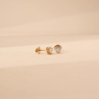 Angled view of heart-shaped lab-grown diamond stud earrings in 18 KT Yellow gold, featuring three-prong heart-cut solitaire diamonds in a timeless romantic design.