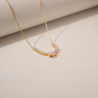 Top view of a diamond necklace in 14KT Yellow Gold, featuring a marquise floral pendant and diamond accents against a beige backdrop.