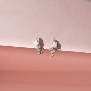 Angled view of 14KT White Gold drop earrings featuring round opal gemstones, diamond accents and cascading round-shaped diamond clusters.