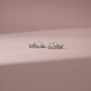 Close-up view of 14KT White Gold drop earrings featuring round opal gemstones, diamond accents and cascading round-shaped diamond clusters.
