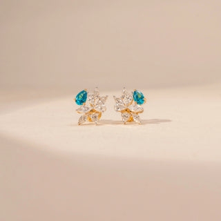 Front view of floral diamond earrings in 14KT yellow gold, featuring pear-shaped blue gemstones and marquise-cut lab-grown diamonds.