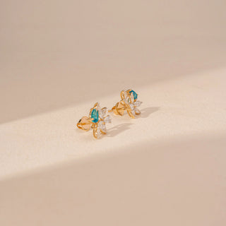 Side view of floral diamond earrings in 14KT yellow gold, featuring pear-shaped blue gemstones and marquise-cut lab-grown diamonds.