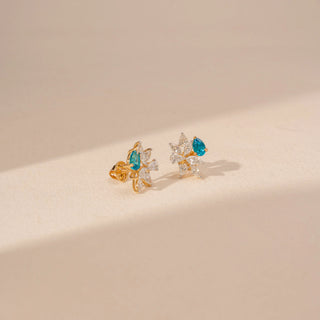 Angled view of floral diamond earrings in 14KT yellow gold, featuring pear-shaped blue gemstones and marquise-cut lab-grown diamonds.