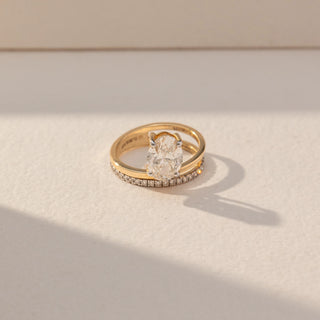 Top view of Oval Solitaire Diamond Ring with Band in 14KT Yellow Gold, featuring a centred oval lab grown diamond with a pavé band. Set on a beige backdrop, the design highlights symmetry and refined brilliance.
