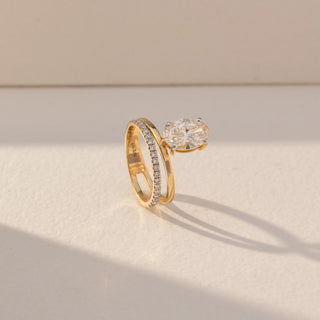 Side view of Oval Solitaire Diamond Ring with Band in 14KT Yellow Gold, featuring a centred oval lab grown diamond with a pavé band. Set on a beige backdrop, the design highlights depth and elegant brilliance.
