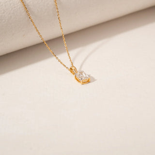 Top view of a diamond pendant in 14KT Yellow Gold, featuring a oval-cut centre stone in a four-prong setting against a beige backdrop.