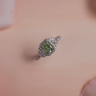 Top view of Reia Verdant Halo Radiant Diamond Ring on a blush-peach background, featuring a radiant-cut green lab-grown diamond surrounded by a halo of marquise and round EF VVS diamonds in 14KT white gold.