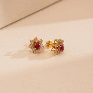Angled view of Reia’s 14 KT Yellow Gold Ruby Floral Cluster Diamond Studs. The layout highlights the warm gold foundation and the architectural diamond-set petals surrounding deep crimson rubies.