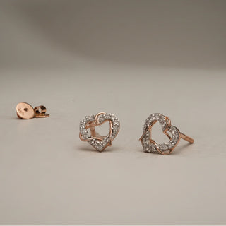 Interlocked Heart diamond stud earrings in 14KT Rose Gold, placed on a neutral surface, featuring two entwined heart motifs paved with EF-VVS lab-grown diamonds.