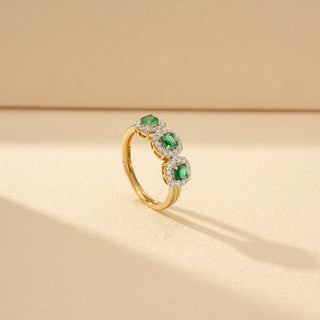 Angled view of a Three-Stone Green Emerald Diamond Ring in 14KT Yellow Gold, featuring three vivid green emerald-cut gemstones.