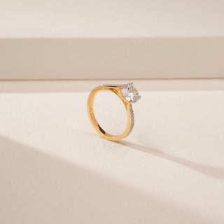 Angled view of a 14KT Yellow Gold diamond ring, featuring a round centre diamond and diamond-set curved shoulders.