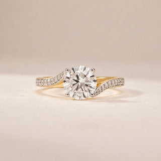 Front view of a 14KT yellow gold ring featuring a round brilliant-cut diamond and curved pavé band.