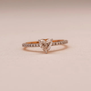 Front view of Reia’s 18 KT Yellow Gold Forever Heart Diamond Solitaire Ring. The centred heart-shaped diamond sits on a pavé-set band against a soft pink surface, showing its romantic sparkle.