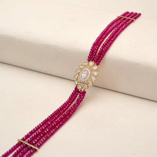 Angled view of a pink beaded diamond bracelet in 18KT Yellow Gold, featuring an oval lab-grown diamond floral centre with round halo accents. Captured against a beige backdrop, the vibrant design radiates elegance.