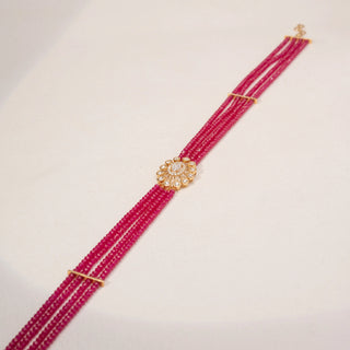 Side view of a pink beaded diamond bracelet in 18KT Yellow Gold, featuring an oval lab-grown diamond floral centre with round halo accents. Captured against a beige backdrop, the sleek design showcases vibrant elegance.