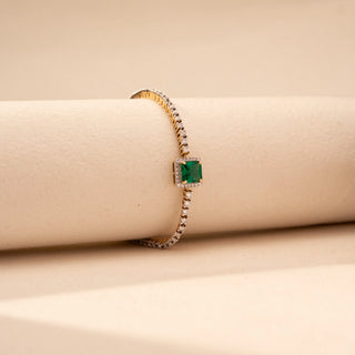 Side view of a round lab-grown diamond tennis bracelet in 14KT white gold, featuring a square emerald centre stone framed by a diamond halo with a continuous row of round brilliant diamonds in an elegant design.