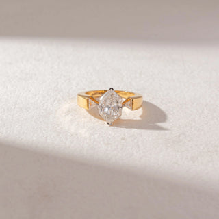 Top view of elongated hexagon diamond ring in yellow gold with tapered side stones, set on a soft neutral surface, highlighting bold structure and clean, radiant brilliance.
