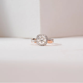 Front close-up of the Intertwined Rose Gold Diamond Ring in 14KT rose gold, featuring a round brilliant center diamond with a cushion halo and twisted dual-tone shank with pavé diamonds on a neutral background.