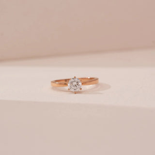 Front view of Reia’s 14 KT Rose Gold Classic Grace Round Diamond Ring. Captured against a cream backdrop, the layout highlights the exceptional sparkle and modern, elegant silhouette.