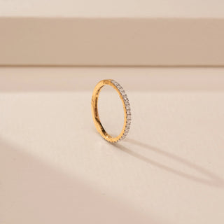 Angled view of a 14KT Yellow Gold diamond ring, featuring a full band of closely set round diamonds.
